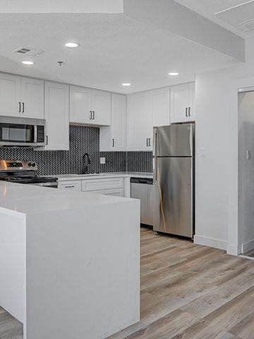 A modern kitchen with a white island and stainless steel appliances.