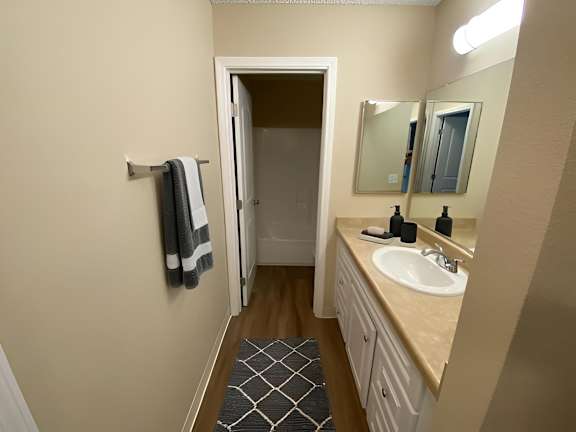 A bathroom with a sink, mirror, and towel rack.