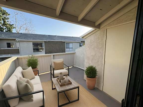 A patio with a white couch, a black table, and a potted plant.