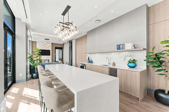 A modern kitchen with a long white island and a large window.