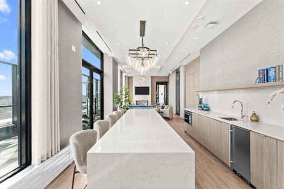 A modern kitchen with a long white island in the middle.
