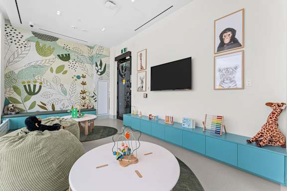 A living room with a green sofa, a white table, and a TV on the wall.