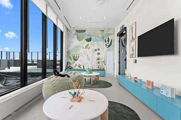 A person is sitting on a bean bag chair in a room with a large mural of plants on the wall.