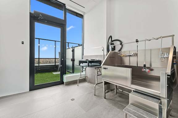 A modern kitchen with stainless steel appliances and a view of the outdoors through a glass door.