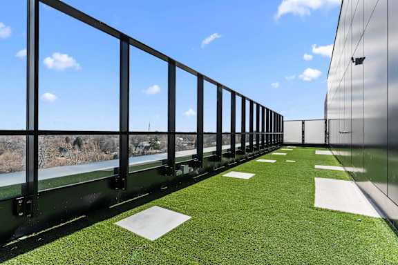 A balcony with a green lawn and a metal railing.