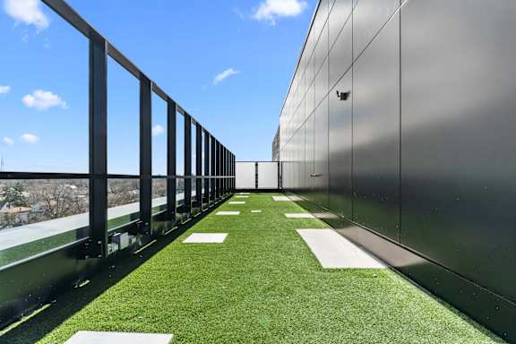 A long balcony with a metal railing and a green lawn.