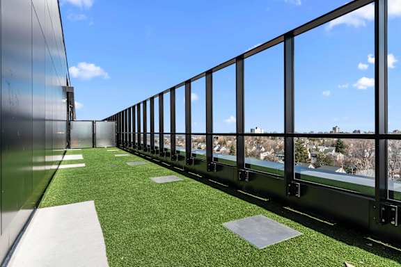 A balcony with a metal railing and a green artificial turf area.