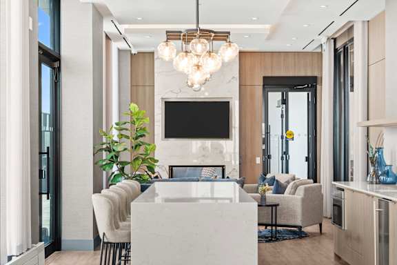 A modern living room with a white marble coffee table and a large flat screen TV mounted on the wall.