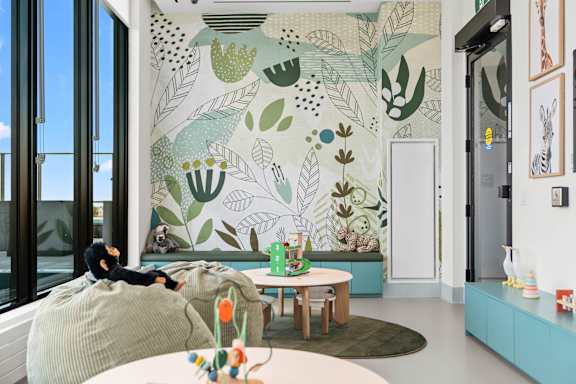 A living room with a large mural of plants on the wall.