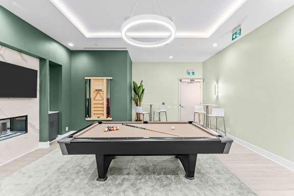 A pool table is in the middle of a room with green walls.
