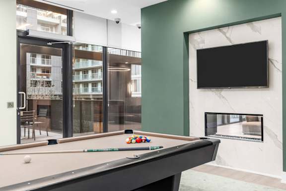 A pool table with a green wall and a television mounted on it.