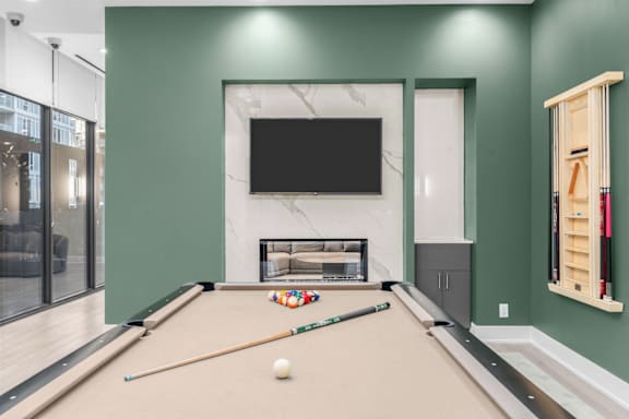 A pool table with a white ball on it and a TV mounted on the wall.