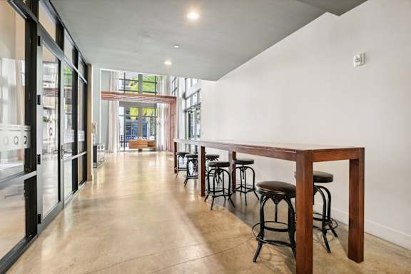 A long wooden table is in the middle of a room with bar stools.