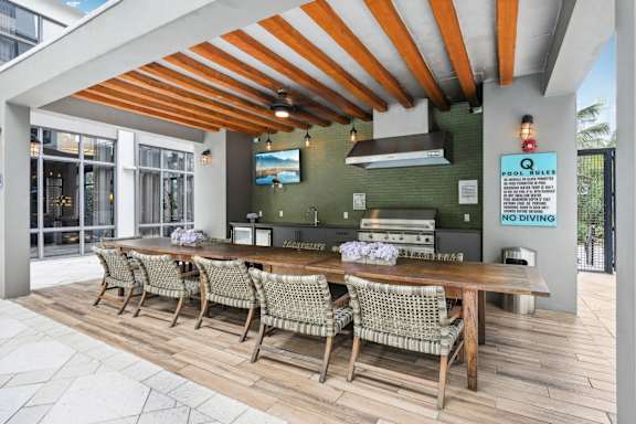 A restaurant with a long wooden table and chairs under a striped roof.