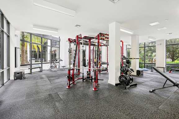 A gym with a red weight machine and a grey floor.