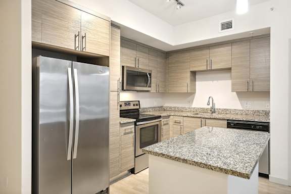 A modern kitchen with a granite countertop and stainless steel appliances.