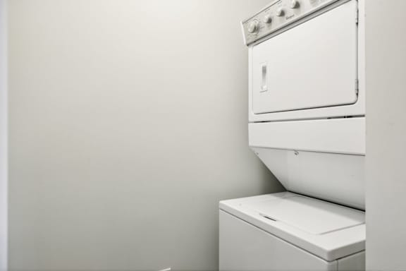 A white stacked washer and dryer is installed in a wall.