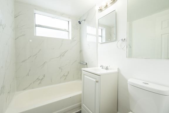 A white bathroom with a tub, sink, and mirror.