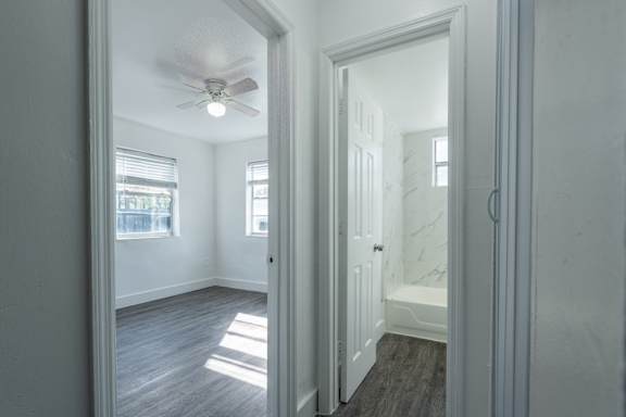 A room with a ceiling fan and a door leading to another room.