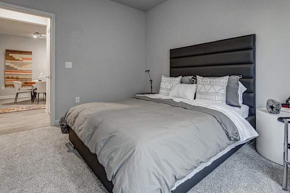 A bedroom with a large bed and a woven wall hanging.