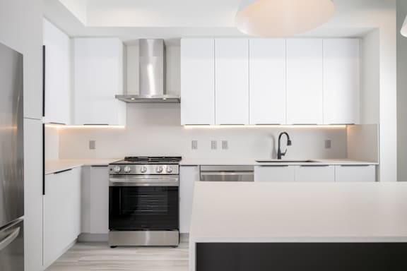A modern kitchen with white cabinets and stainless steel appliances.