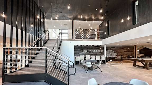 A modern interior space with a staircase, tables, and chairs.
