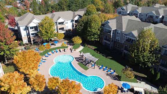 An aerial view of a pool surrounded by trees and chairs.