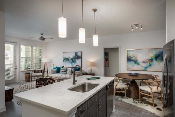 A kitchen with a marble countertop and a dining table with chairs.