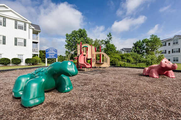 A playground with a green dinosaur and a pink pig.