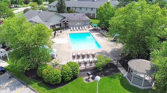 A pool surrounded by trees and a gazebo.