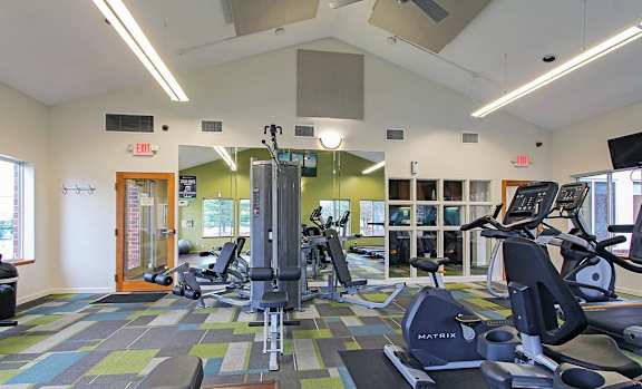 A gym with a variety of equipment including treadmills and weights.