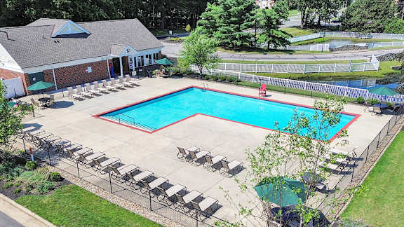 A pool surrounded by a fence and chairs.