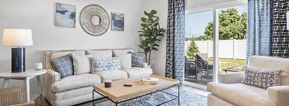 A living room with a sofa, a coffee table, a side table, and a potted plant.