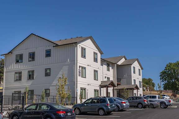 A row of cars parked in front of a white building.