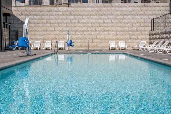 A pool with blue water and white chairs.