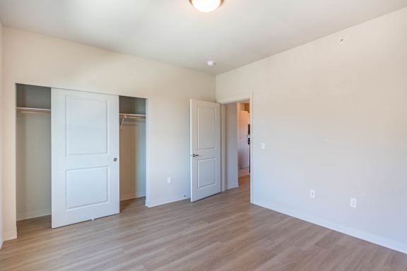 A room with white walls and wooden floors with three white doors.