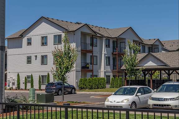 A row of townhouses with cars parked in front.