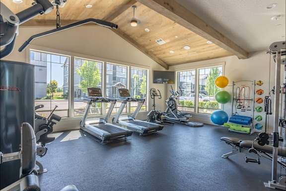 A spacious gym with a variety of exercise equipment and a large window overlooking the outdoors.