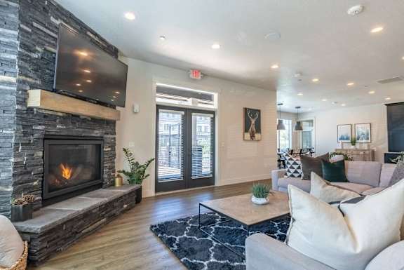A modern living room with a stone fireplace and a flat screen TV mounted above it.