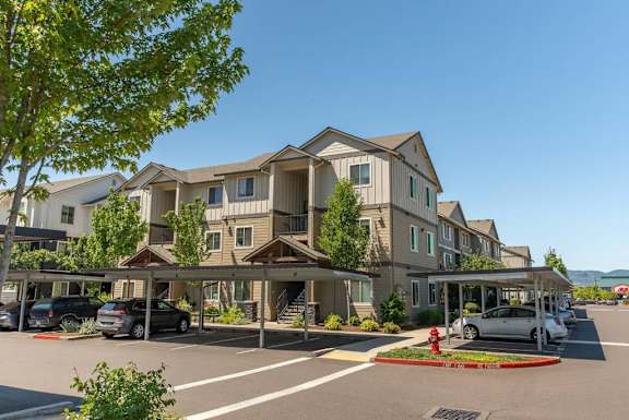 A large apartment complex with a parking lot in front.
