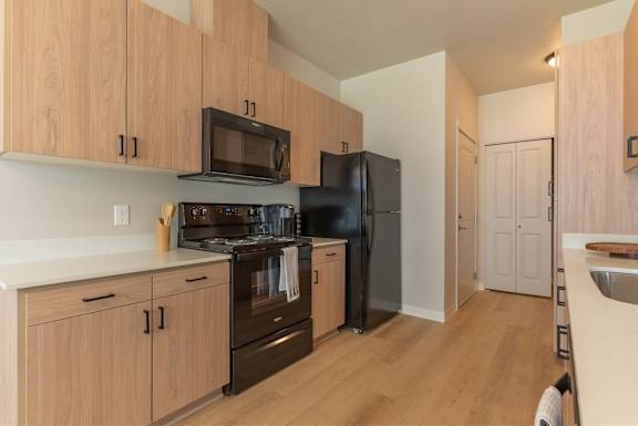 A kitchen with wooden cabinets and black appliances.
