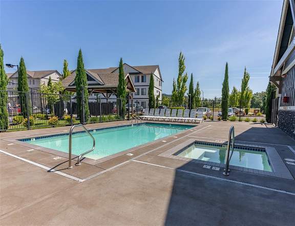 A large outdoor swimming pool with a slide and a hot tub.