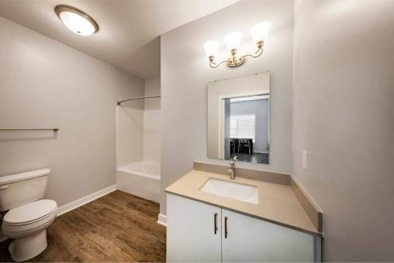 A bathroom with a toilet, sink, and mirror.