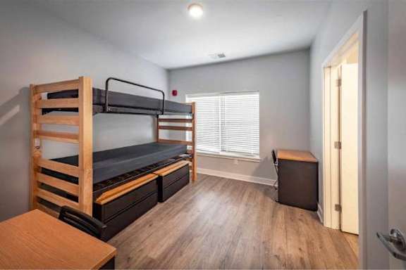 A room with a bunk bed and a desk.