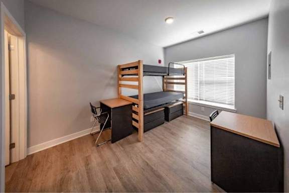 A room with a bunk bed and a desk.