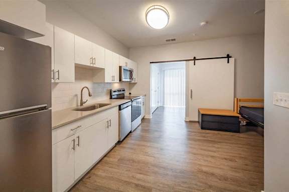 A kitchen with white cabinets and a stainless steel refrigerator.