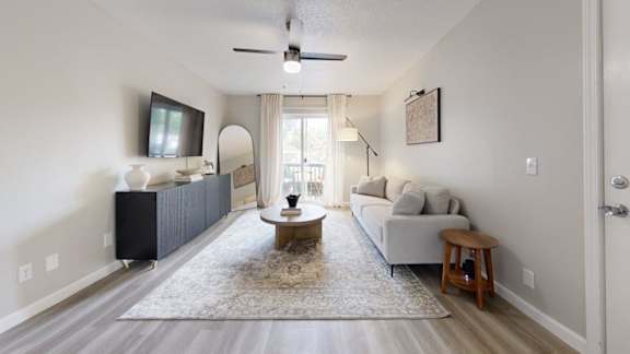 A living room with a white couch, a coffee table, and a television.
