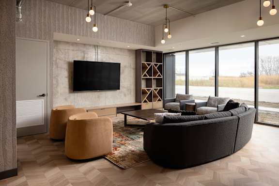 A modern living room with a large couch, a television, and a rug.at Damask, Ontario, N8S 0B7