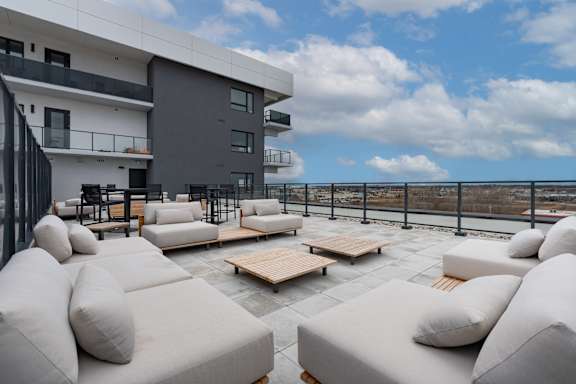 A modern outdoor seating area with white cushioned furniture and a view of the city at Damask, Windsor Ontario