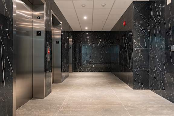 A long hallway with marble floors and walls and elevators on the side at Damask, Ontario